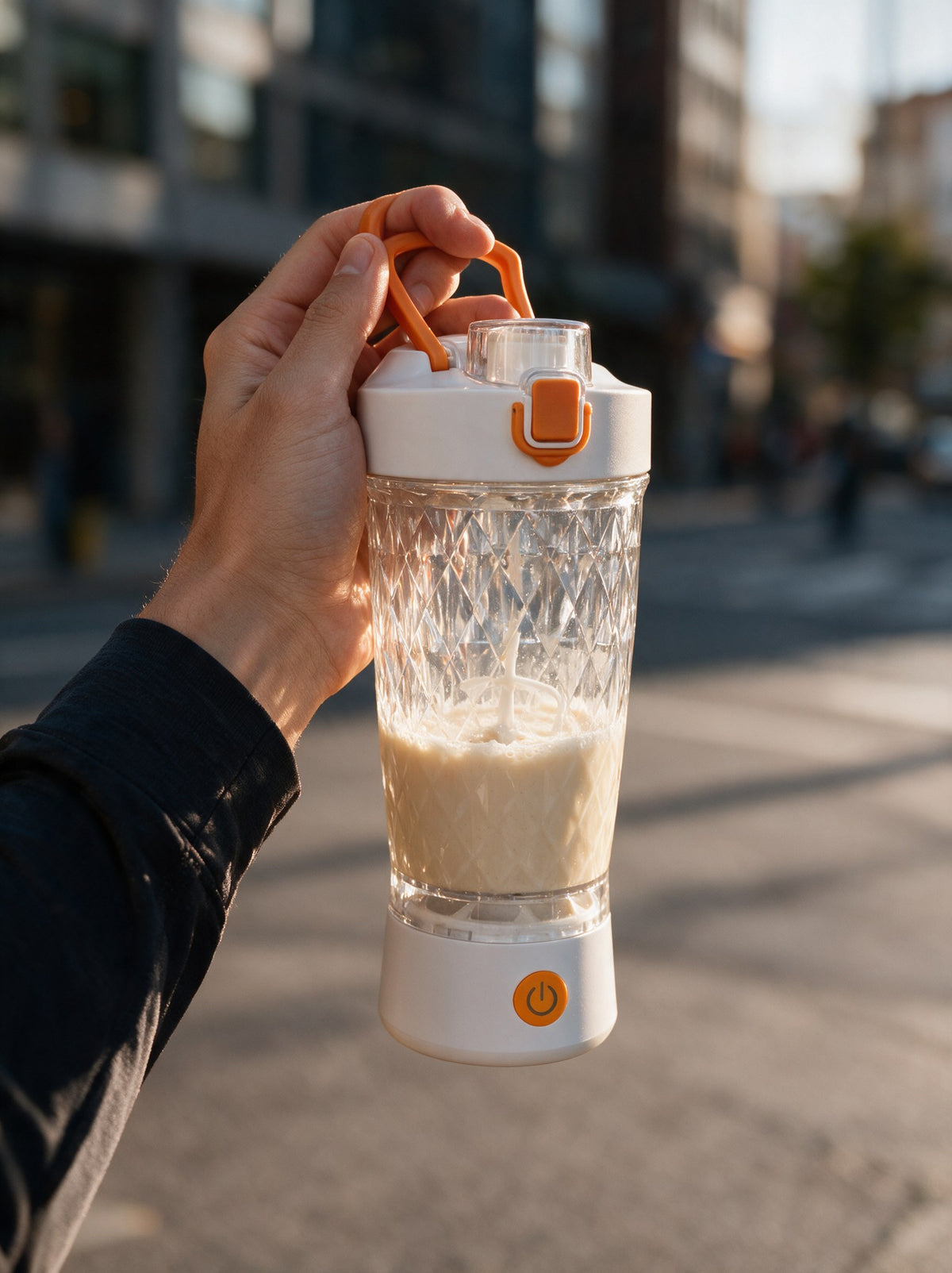 Hand hält den VELORA Volt Akku-Shaker mit frisch gemixtem Shake unterwegs in der Stadt