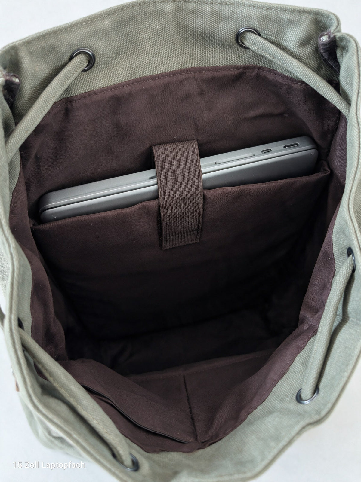 Blick von oben ins geöffnete Hauptfach mit dunkelbraunem Stofffutter, ein Laptop steckt im eingenähten Laptopfach für Laptops bis 15 Zoll